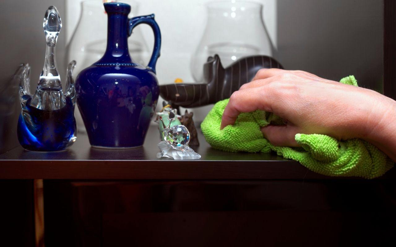 A person using a microfiber cloth to remove dust from a wooden surface in a clean, dust-free home.